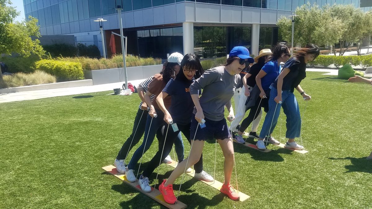 Real teammates coordinate their steps on shared walking skis outdoors